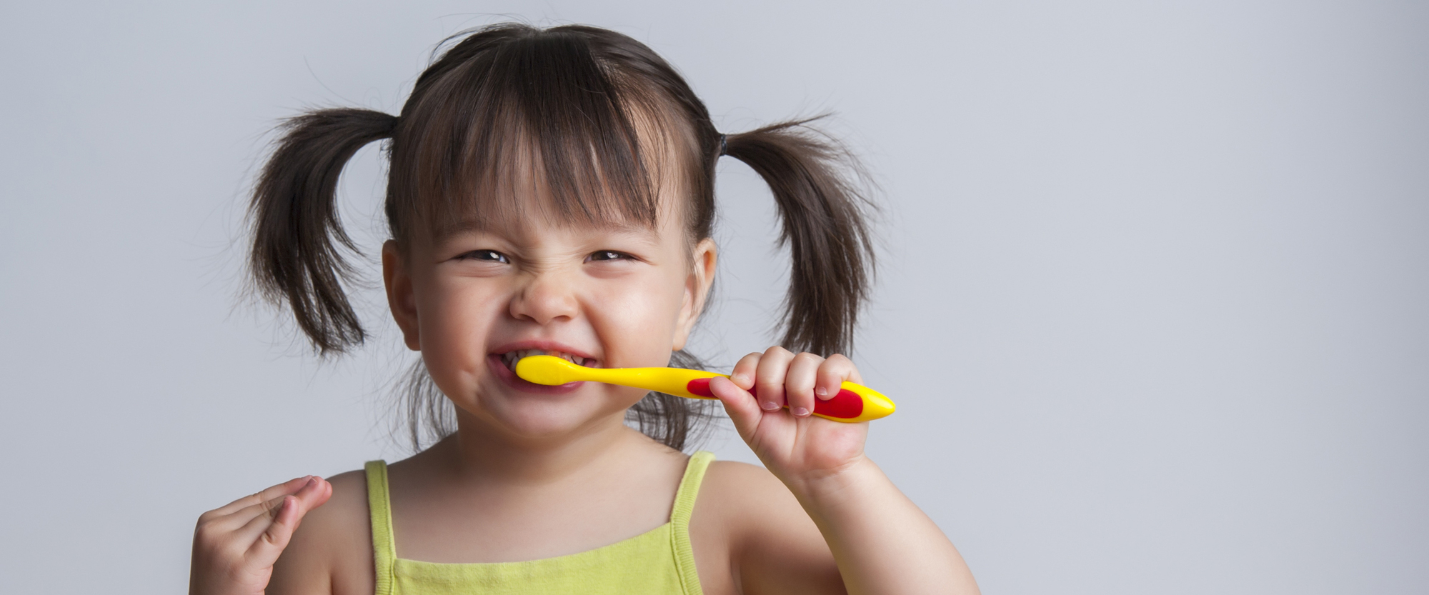Toddler smiling while brushing her teeth