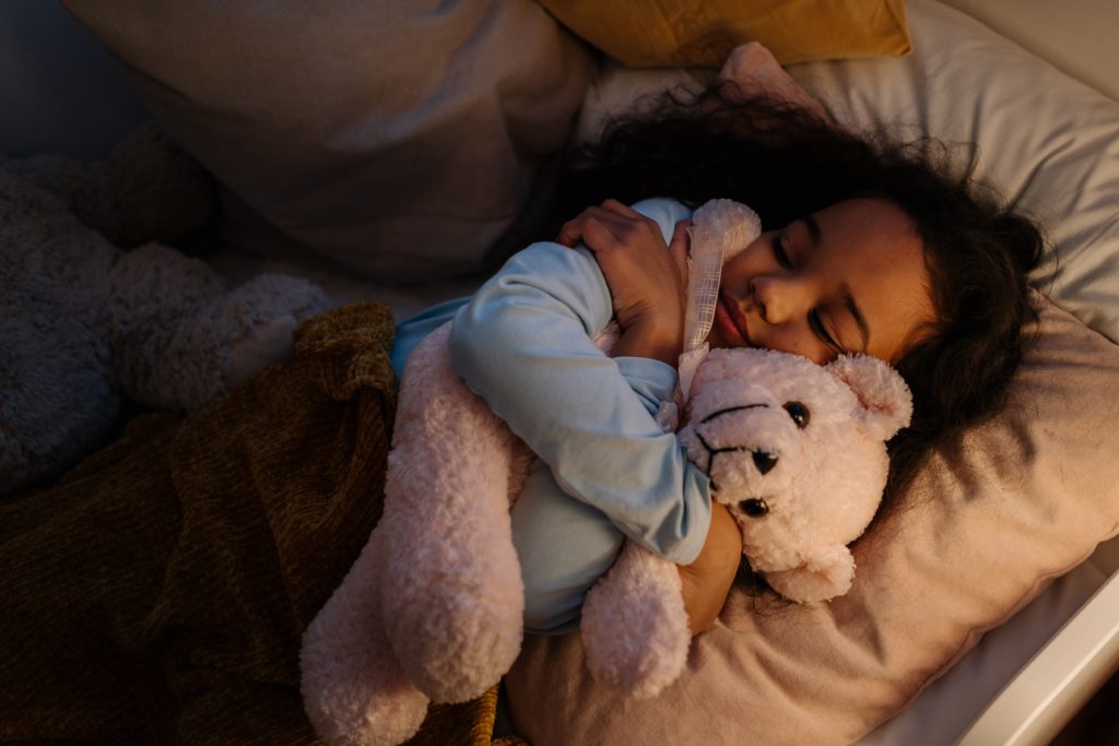 child sleeping and hugging their bear